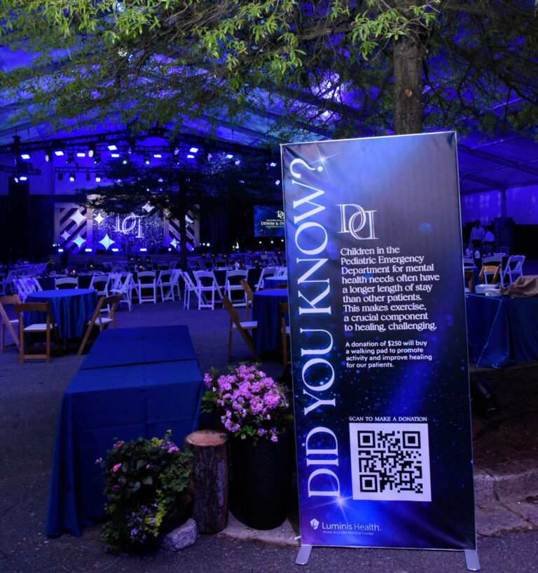 Denim and Diamonds Bash event setup with decorated tables, chairs, and informational sign with QR code supporting pediatric mental health at Luminis Health